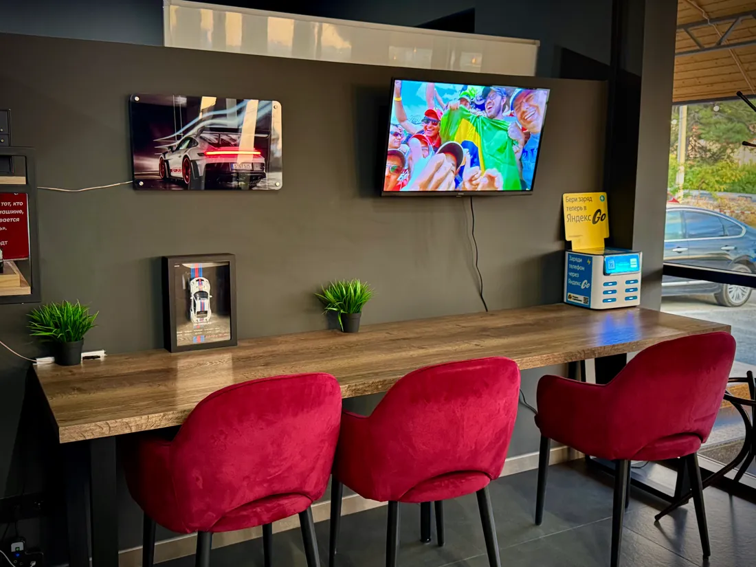 Длинный стол, красные кресла и автомобильные постеры в кафе KarCoffee